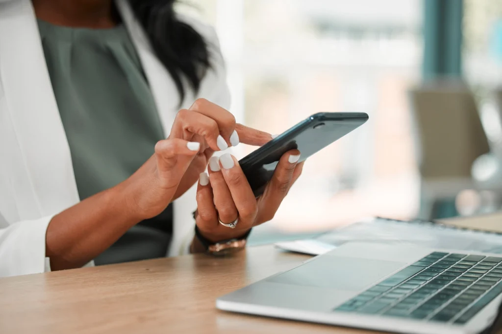 woman wearing a white coat while holding a phone and doing sms texting